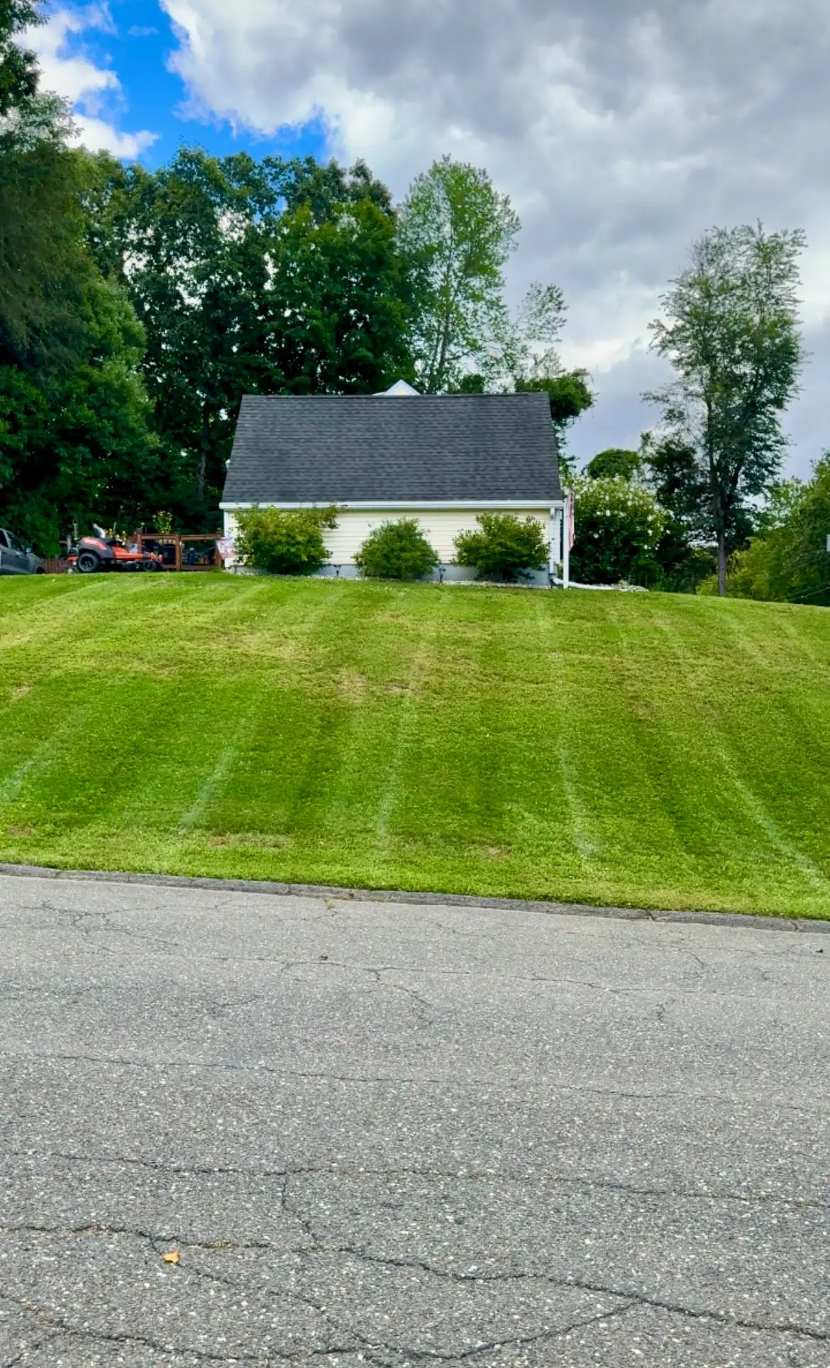 A well-maintained landscaped yard with green lawn, fresh mulch beds, and stone walkway on a New England property